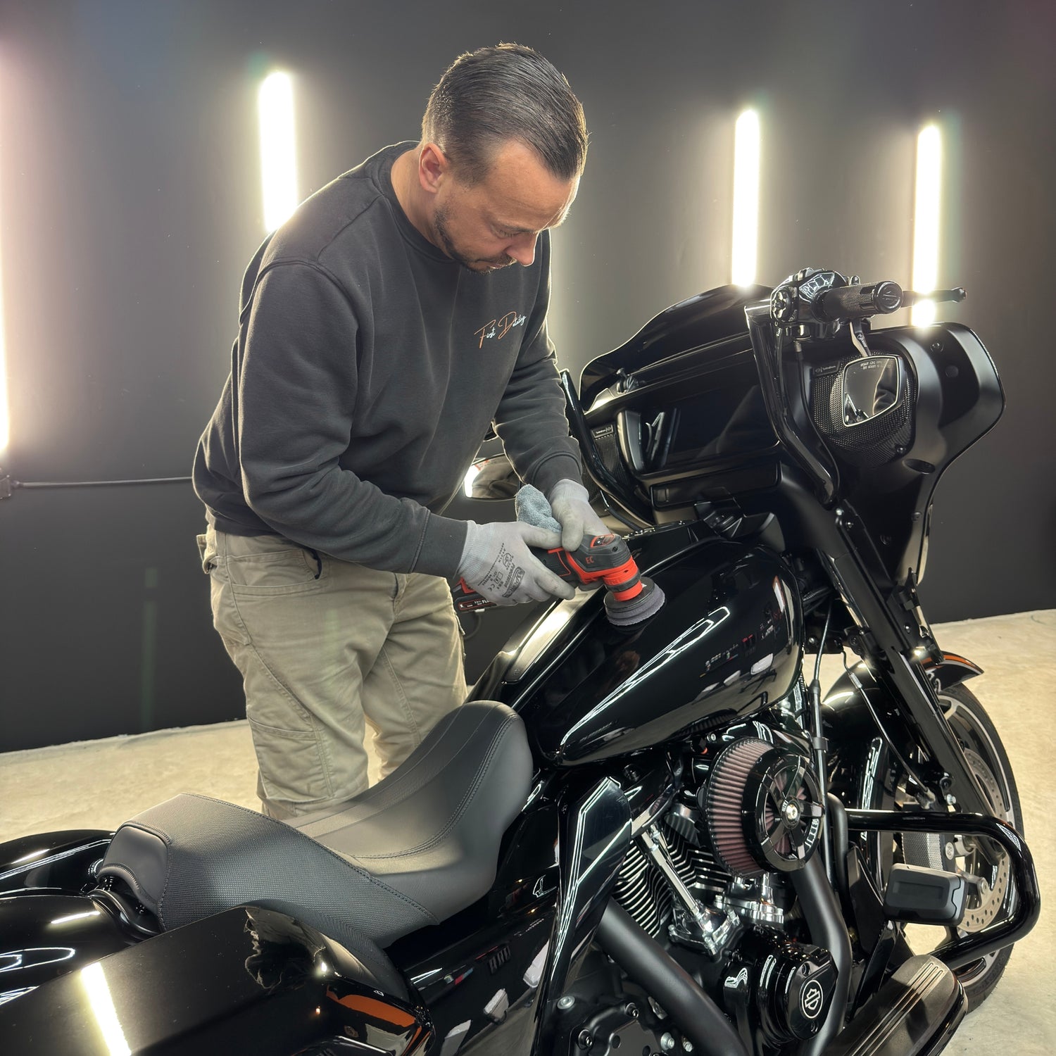 Das Bild zeigt wie ein Mann eine Harley poliert